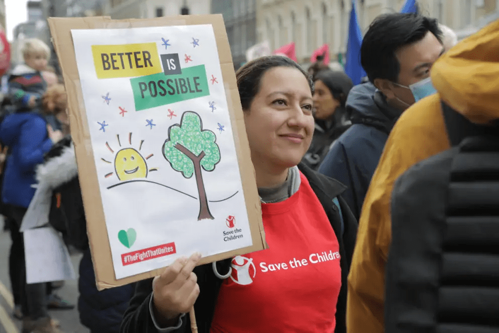 mujer con un carte de Save the Children